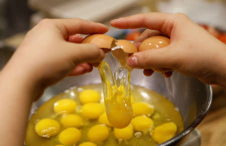 A pastry chef breaks an egg as she prepares to bake a cake at a bakery in Seoul, South Korea, December 22, 2016. REUTERS/Kim Hong-Ji