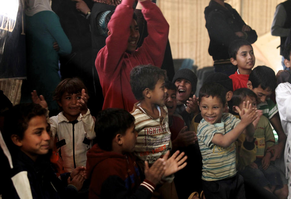 Syrian refugee children clap as they watch performance by Mabsutins, a comedian group from Europe, at Zaatari refugee camp near the Syrian border in Mafraq, Jordan, Sunday, Dec. 1, 2013. (AP Photo/Mohammad Hannon)