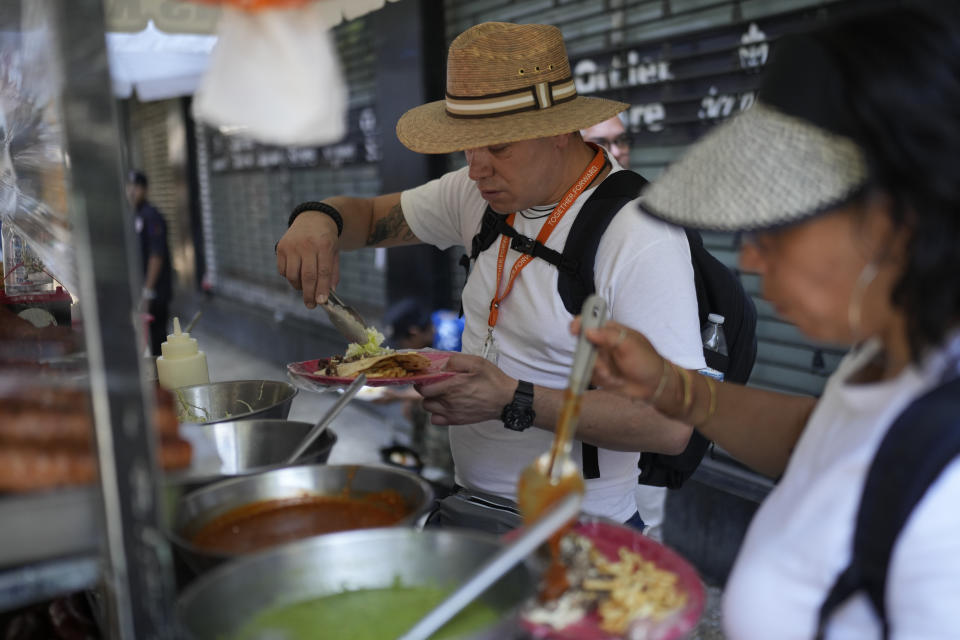 La gente come tacos en un puesto en la acera de la Ciudad de México, el lunes 3 de junio de 2024, el día después de las elecciones generales. (AP Foto/Matías Delacroix)