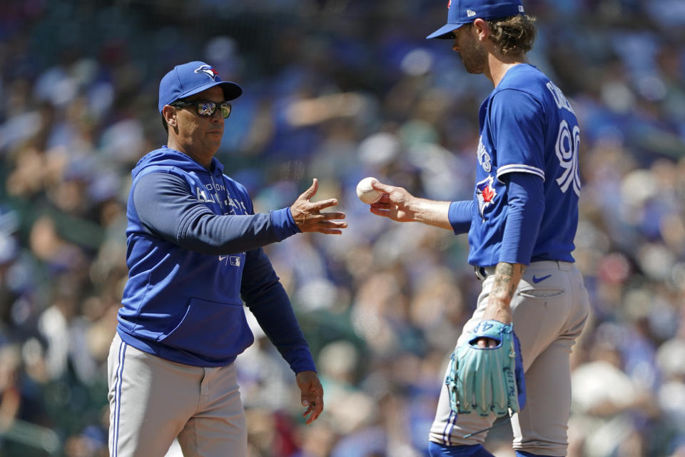 El pitcher de los Azulejos de Toronto Adam Cimber (derecha) es sacado por el manager Charlie Montoyo durante el juego contra los Marineros de Seattle, el 10 de julio de 2022. (AP Foto/Ted S. Warren)