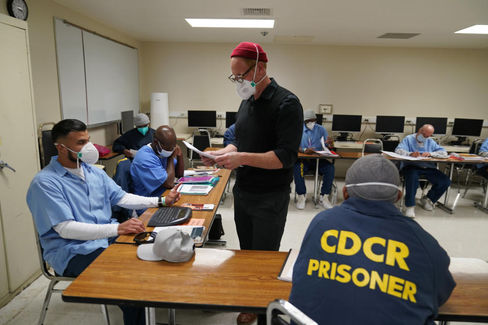 FILE - Instructor Douglas Arnwine hands back papers with comments to his incarcerated students during a Mount Tamalpais College English class called Cosmopolitan Fictions at San Quentin State Prison on April 12, 2022, in San Quentin, Calif. California Gov. Gavin Newsom plans to transform a state prison home to the nation's largest number of inmates on death row into a facility where prisoners can receive education, training and rehabilitation before reentering society. Newsom's office announced the new plans for San Quentin State Prison on Thursday, March 16, 2023. (AP Photo/Eric Risberg, File)