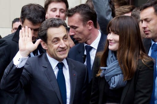 France's incumbent president and Union for a Popular Movement (UMP) candidate for the presidential election Nicolas Sarkozy (left) arrives with his wife Carla Bruni Sarkozy at a polling station on May 6, in Paris