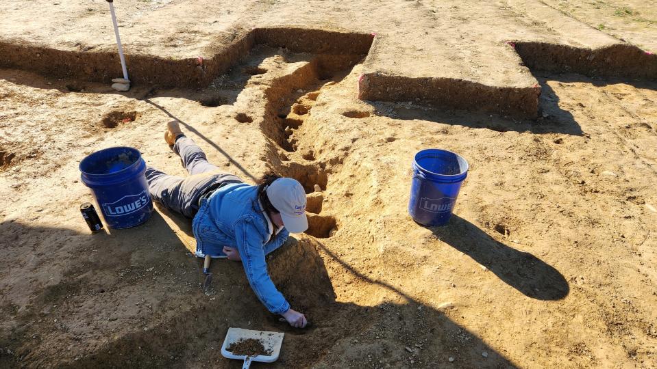 In this photo provided by John Crawmer, Jane C. Skinner excavates post holes at the bottom of a stockade trench, Thursday, Oct. 27, 2022, in York, Pa. Researchers say they have solved a decades-old riddle by finding remnants of the stockade and therefore the site of a prison camp in York, that housed British soldiers for nearly two years during the American Revolutionary War. (John Crawmer via AP)