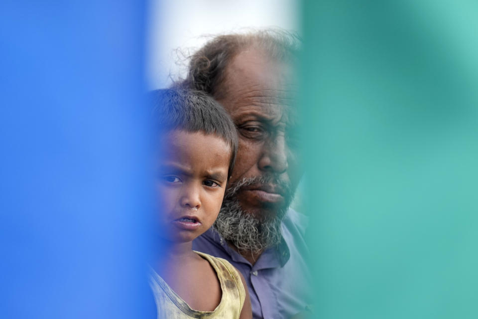 Kamaluddin y su hijo de cinco años, Azrahul Islam, miran mientras personal médico asiste a su esposa, Jahanara Khatoon, a dar a luz en un barco en el río Brahmaputra, en el estado nororiental indio de Assam, el miércoles 3 de julio de 2024. (AP Foto/Anupam Nath)