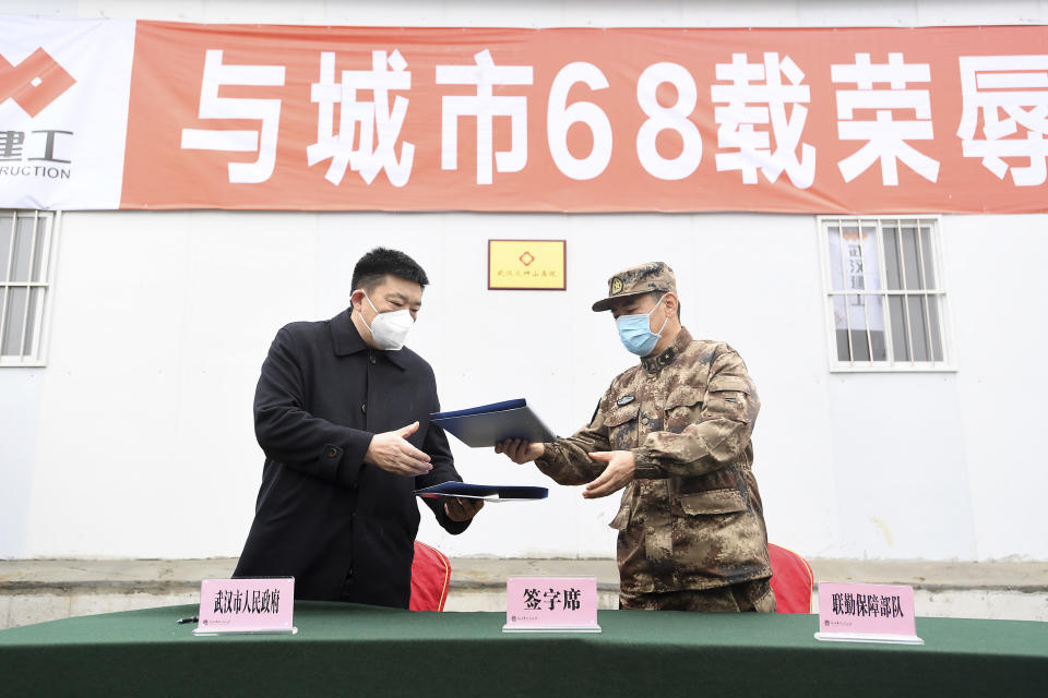 Zhou Xianwang, left, the mayor of Wuhan, exchanges documents with Bai Zhongbin, right, deputy commander-in-chief of China's People's Liberation Army (PLA) Joint Logistic Support Force, during a handover ceremony at the Huoshenshan temporary field hospital in Wuhan in central China's Hubei Province, Sunday, Feb. 2, 2020. The Philippines on Sunday reported the first death from a new virus outside of China, where authorities delayed the opening of schools in the worst-hit province and tightened quarantine measures in a city that allow only one family member to venture out to buy supplies. (Chinatopix via AP)