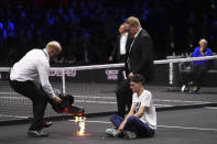 A protester lights a fire on the court on day one of the Laver Cup at the O2 Arena in London, Friday Sept. 23, 2022. (John Walton/PA via AP)