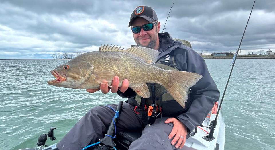 kayak fisherman holds a smallmouth bass