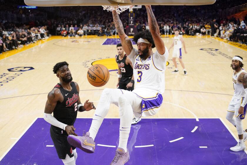 Los Angeles Lakers forward Anthony Davis (center) dunks while guarded by Portland Trail Blazers center Deandre Ayton during the second half of an NBA basketball game on Sunday, Nov. 12, 2023, in Los Angeles.  (AP Photo/Mark J. Trier)