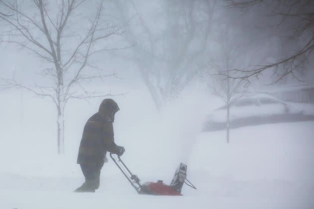 A person clears snow as a winter storm rolls on Saturday in Amherst, New York. A battering winter storm has knocked out power to hundreds of thousands of homes homes and businesses across the United States on Saturday.