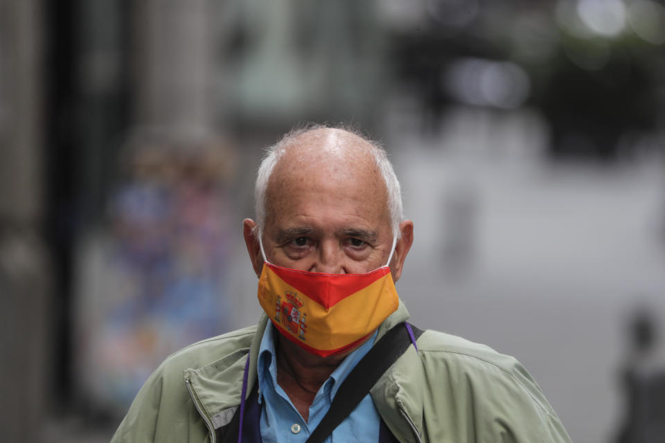 A man wearing a face mask to prevent the spread of coronavirus decorated with the Spanish flag stands in a street in downtown Madrid, Spain, Friday, Sept. 18, 2020. With more than 11,000 new daily coronavirus cases, the attention in Spain is focusing on its capital, where officials are mulling localized lockdowns and other measures to bring down the curve of contagion. (AP Photo/Manu Fernandez)