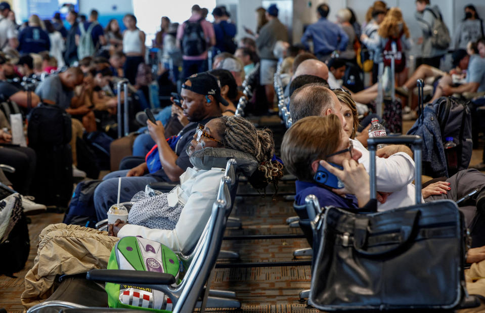 机场休息室人满为患，背景中排着长队的旅客。