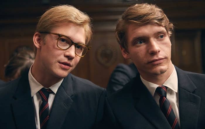 Joe Alwyn, wearing glasses and a prep school uniform, sits next to a boy dressed the same