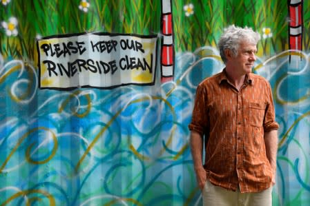 Activist, environmentalist, community leader and undertaker Peter McFadyen stands next to a painted storage unit on the banks of the River Frome, in Frome