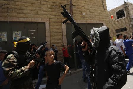 Palestinian militants take part in the funeral of Palestinian Mohammed Abu Latifa, 19, in Qalandiya refugee camp, near the West Bank city of Ramallah July 27, 2015. Abu Latifa, wanted on suspicion of planning a militant attack, fell to his death from a rooftop on Monday as he fled from police in the occupied West Bank, Israeli police said, an account disputed by a witness. REUTERS/Mohamad Torokman