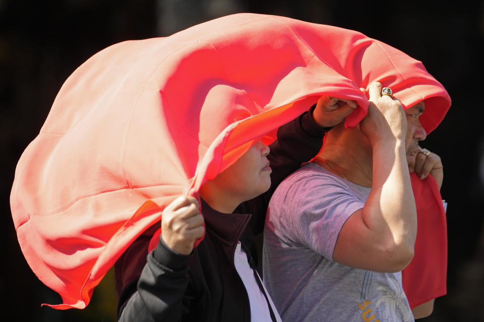 FILE - A man and woman use a cloth over their heads to protect themselves from the sun in Manila, Philippines on April 29, 2024. Month after month, global temperatures are setting new records. (AP Photo/Aaron Favila, File)