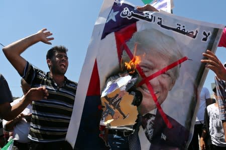 Palestinian demonstrators burn a crossed-out poster depicting U.S. President Trump during a protest against Bahrain's workshop for U.S. Middle East peace plan, in the southern Gaza Strip
