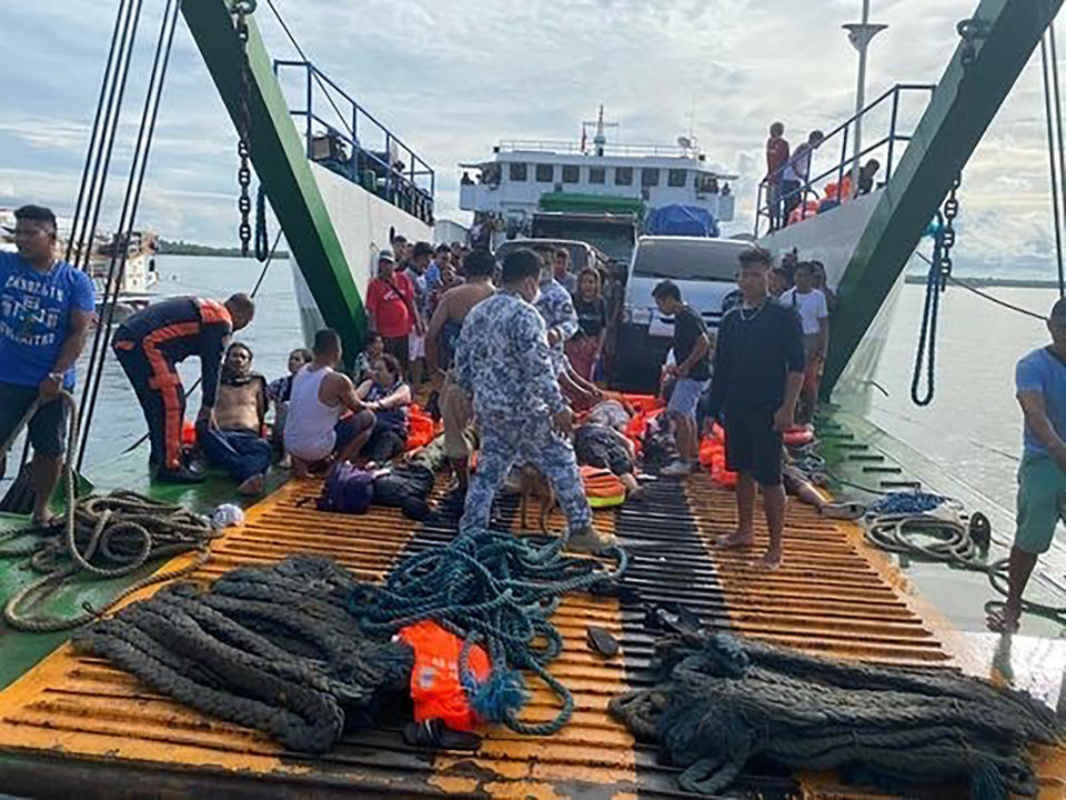 In this photo provided by the Philippine Coast Guard, passengers are checked after being rescued at the port of Real, Quezon province, Philippines Monday, May 23, 2022. A passenger ship caught fire as it nears their port of destination in Real town killing several people on board. (Philippine Coast Guard via AP Photo)