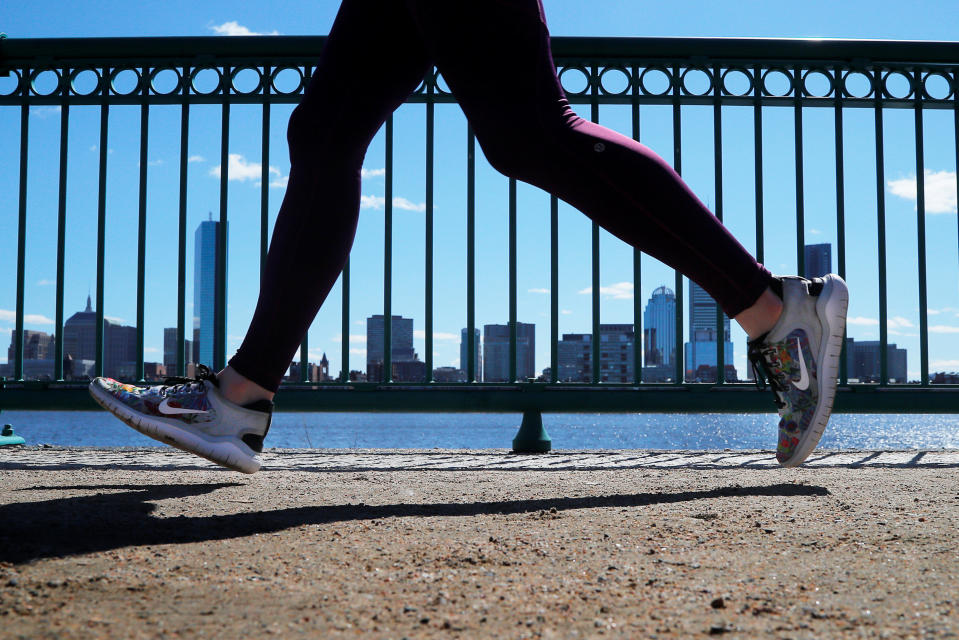 A jogger wearing Nike shoes runs past the Boston skyline along the Charles River in Cambridge, Massachusetts, U.S., March 18, 2019.   REUTERS/Brian Snyder