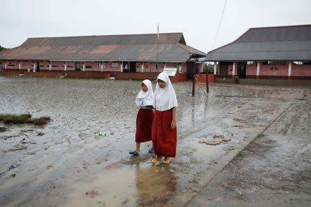 Students walk in the yard of the Pantai Bahagia Elementary School, before tide comes in, in Bekasi, West Java province, Indonesia, February 1, 2018. REUTERS/Darren Whiteside