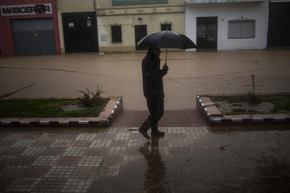 A man walks by a flooded roadway at the village of Campillos, Spain, where heavy rain and floods have caused severe damage and the death of a firefighter according to Spanish authorities Sunday, Oct. 21 2018. Emergency services for the southern region of Andalusia say that the firefighter went missing when his truck overturned on a flooded road during heavy rains that fell through the night, and his body was found after a search Sunday morning. (AP Photo/Javier Fergo)