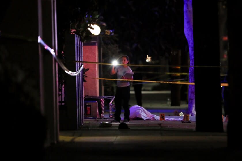 El Monte, CA - June 14: Investigators look over the body of a suspect at a scene after a shooting which left two officers and the suspect dead on Tuesday, June 14, 2022 in El Monte, CA. (Robert Gauthier / Los Angeles Times)