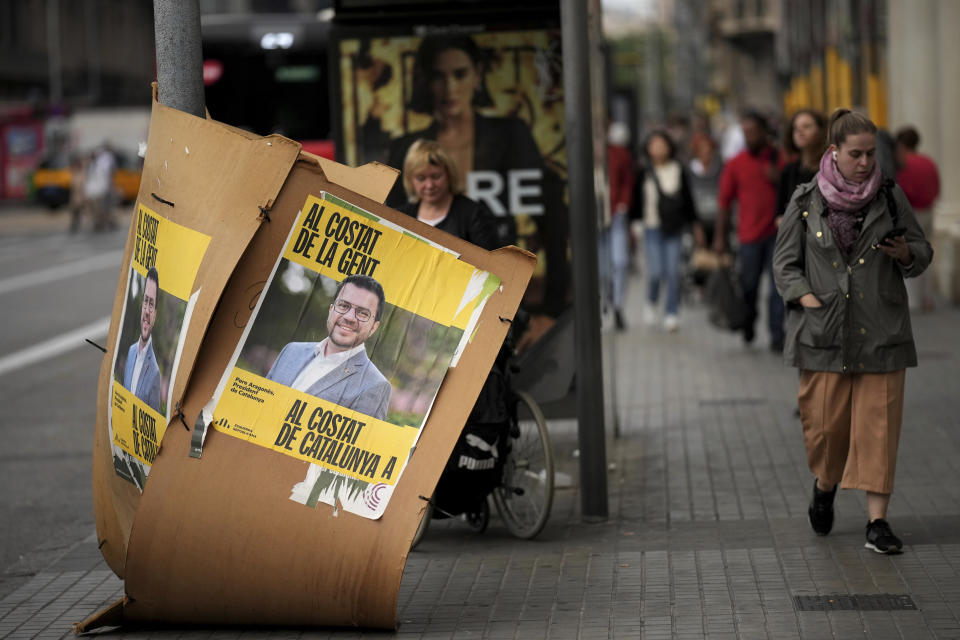 People walk past electoral posters showing a portrait of Catalan president and ERC candidate Pere Aragonès in downtown Barcelona, Spain, Thursday, May 9, 2024. Some nearly 6 million Catalans are called to cast ballots in regional elections on Sunday that will surely have reverberations in Spain's national politics. (AP Photo/Emilio Morenatti)
