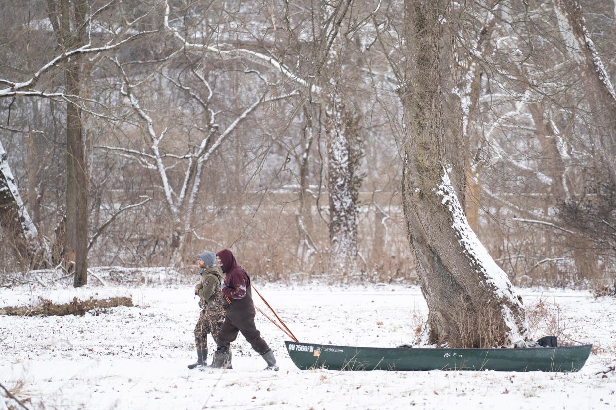 Two Columbus men, Ed Massie, left, of the South Side and Andrew Hunt  of Clintonville, right, pull their canoe alongside the Olentangy Trail in Worthington on Friday, Jan. 19, 2024.  The two were making their way down the river from their starting point in Delaware when they hit ice near Interstate 270 and had to go the rest of the way to Whetstone Park on foot, pulling the canoe behind them.