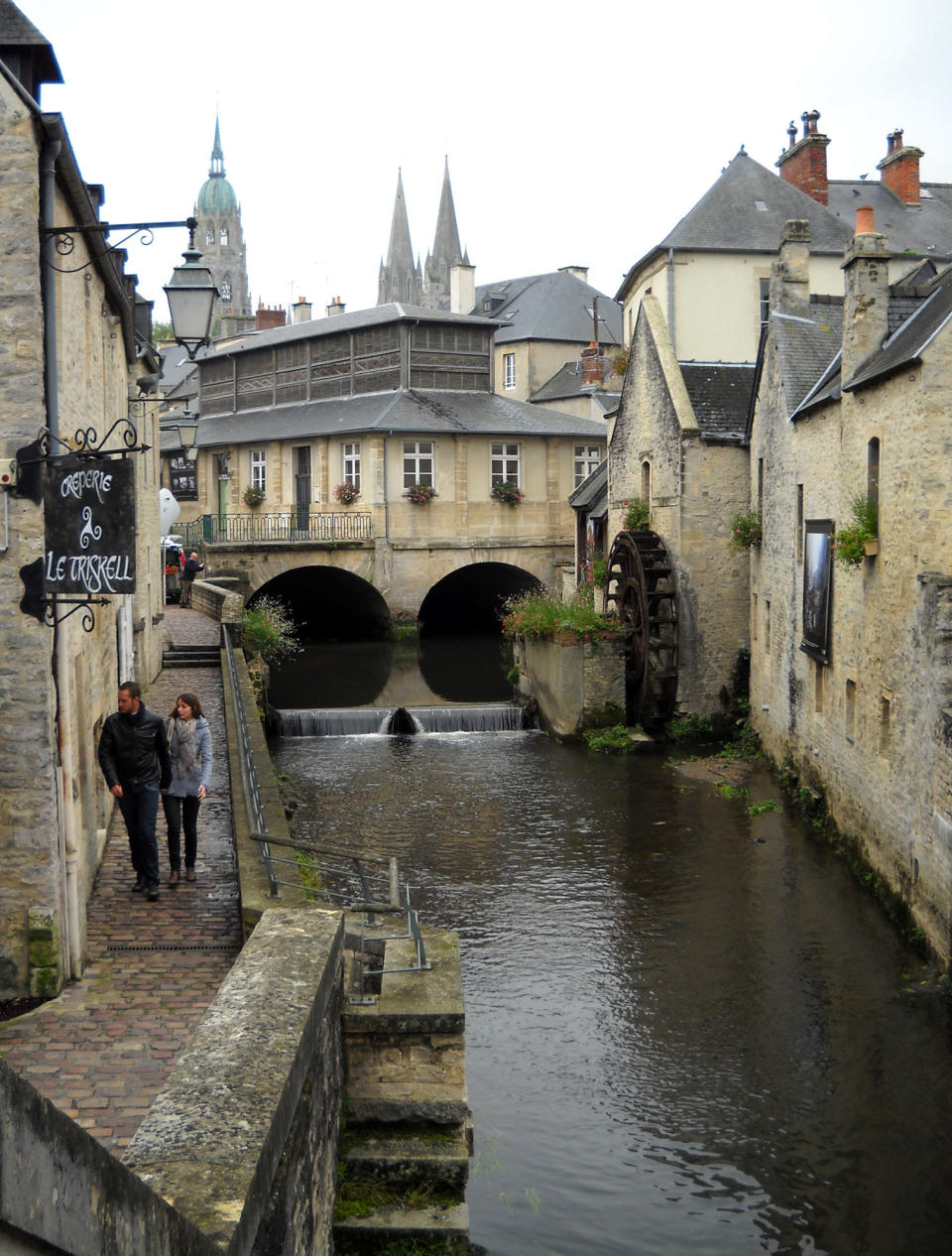 This Oct. 11, 2013 photo shows pedestrians along the River Aure in Bayeux, France. The charming town sits just a few miles from the beaches of Normandy where Allied forces invaded on D-Day during World War II in 1944. (AP Photo/Kathy Matheson)