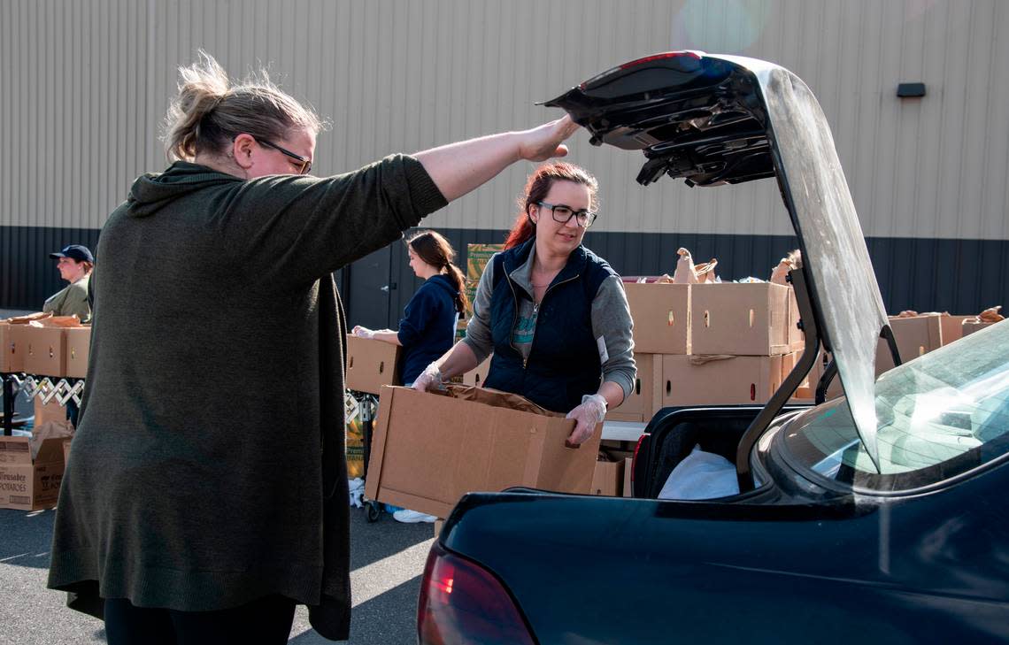 Volunteers Lisa Sanders, left, and Abby Grisham, right, load boxes of food into cars during Second Harvest’s drive-thru food distribution March 24, 2020.