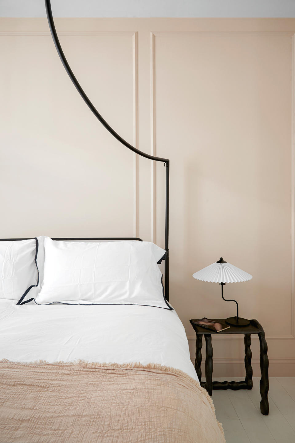 Beige bedroom with black metal bed frame and dark wood bedside table