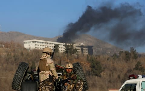 Afghan security forces keep watch as smoke rises from the Intercontinental Hotel on Sunday  - Credit: OMAR SOBHANI/ REUTERS