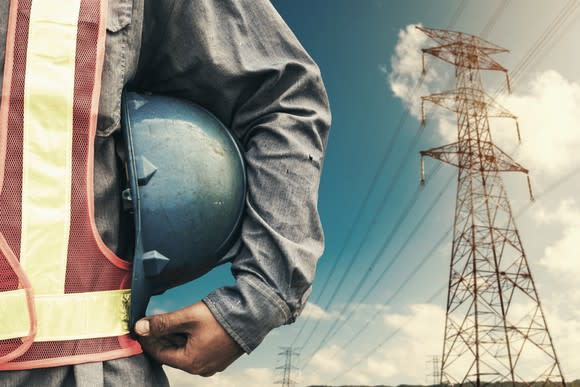 The torso of a man with a high voltage power line in the background