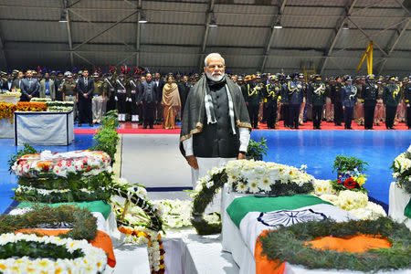 India's Prime Minister Narendra Modi pays tribute as he stands next to the coffins containing the remains of Central Reserve Police Force (CRPF) personnel who were killed after a suicide bomber rammed a car into a bus carrying them in south Kashmir on Thursday, at Palam airport in New Delhi, India, February 15, 2019. India's Press Information Bureau/Handout via REUTERS