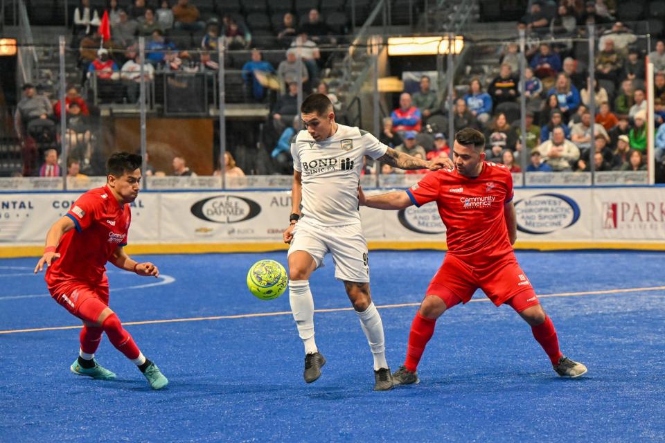 Florida defender Lucas Montalres dribbles between two Kansas City defenders during a Major Arena Soccer League game Saturday night in Missouri. The Tropics ended up winning the game, 6-5.