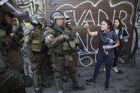 An anti-government demonstrator screams at riot police in Santiago, Chile, Tuesday, Oct. 22, 2019. Protesters defied an emergency decree and confronted police in Chile's capital continuing disturbances that have left at least 15 dead. (AP Photo/Rodrigo Abd)