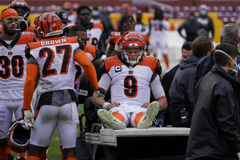 Joe Burrow (9) is consoled by teammates as he is carted off the field during the second half of an NFL football game against the Washington Football Team, Sunday, Nov. 22, 2020, in Landover. Burrow was carted off the field with a left knee injury. (AP Photo/Susan Walsh)