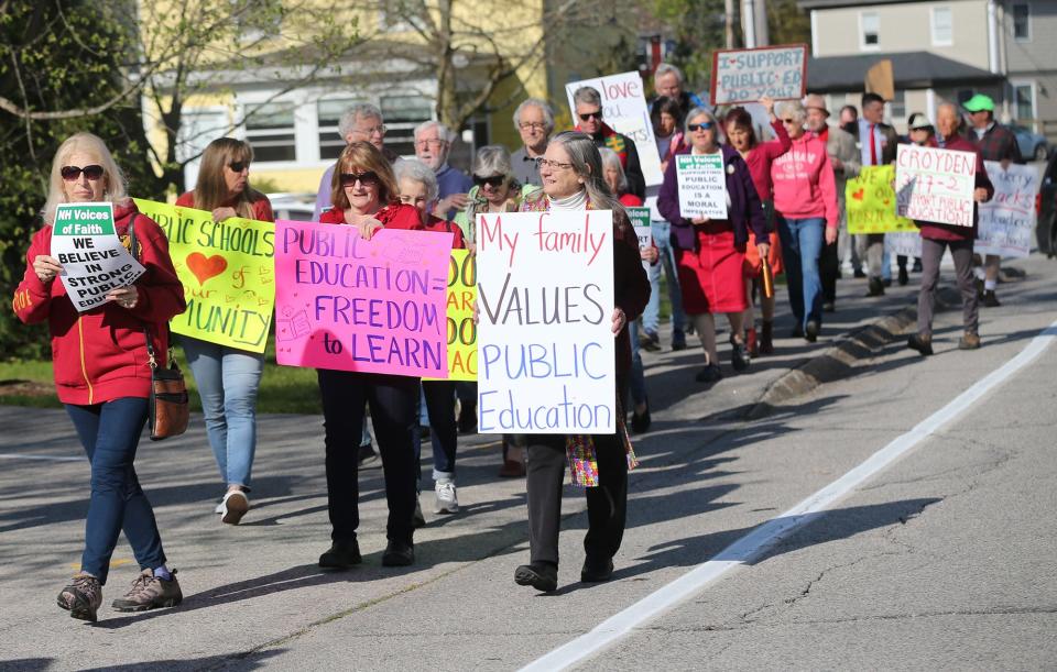 People hold signs in support of public schools and protesting New Hampshire Education Commissioner Frank Edelblut in Durham Thursday, May 12, 2022, before a state Board of Education meeting at Oyster River Middle School.