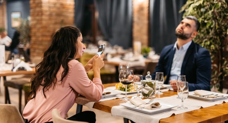 Couple ignoring each other at table. (Getty Images)