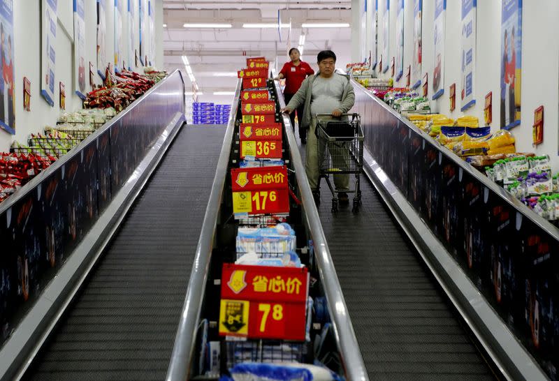 FILE PHOTO: Shoppers ride on a travelator at a supermarket in Beijing