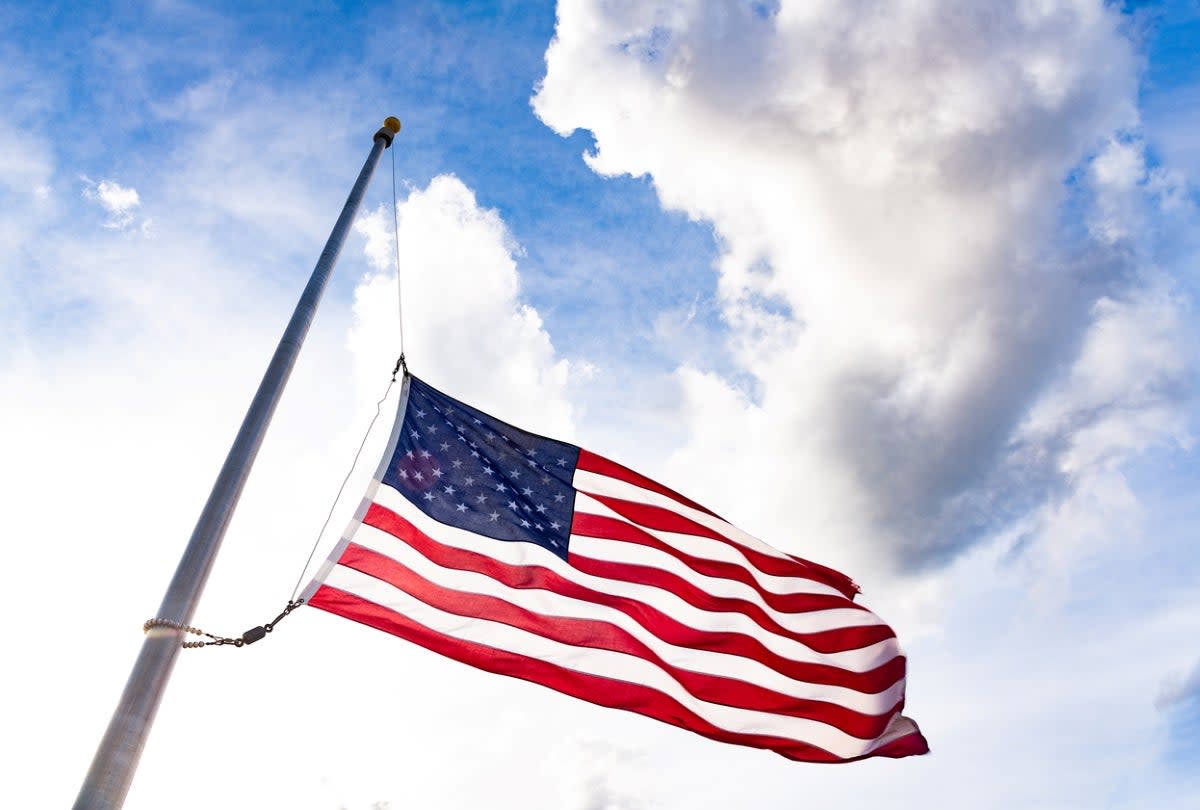 American flag at half mast with clear blue sky