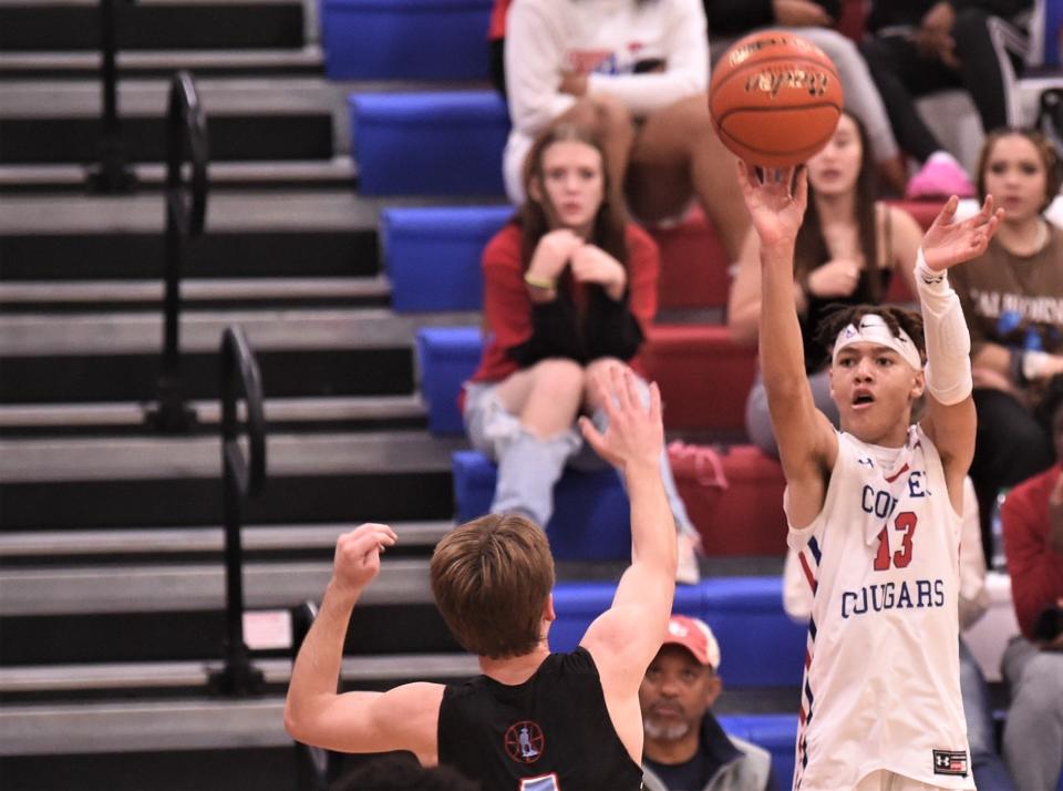 Cooper's Kam Gray, right, shoots a 3-point goal over Lubbock Monterey's Will Collier in the first half. Monterey beat the Coogs 40-37 in the District 4-5A game Jan. 6 at Cougar Gym.