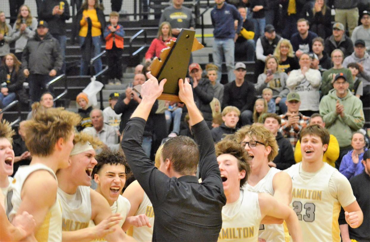 The Hamilton boys basketball team celebrates winning districts on Friday at Hamilton.