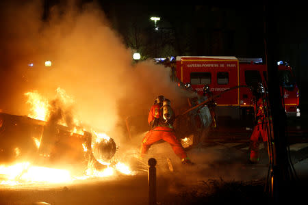 Firemen extinguish burning cars set afire by protesters wearing yellow vests, a symbol of a French drivers' protest against higher diesel fuel taxes, during clashes near the Place de l'Etoile in Paris, France, December 1, 2018. REUTERS/Stephane Mahe