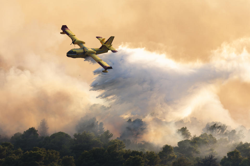 A firefighting plane sprays water to extinguish wildfire at Ciovo island, Croatia, Thursday, July 27, 2023. A large fire is reported on the island of Ciovo, close to Split on the Croatian Adriatic coast. (AP Photo/Miroslav Lelas)
