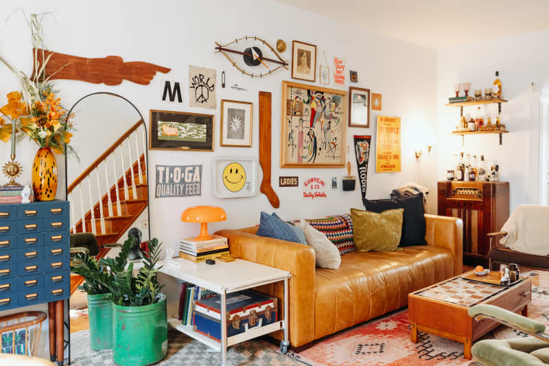 Leather couch anchors seating area with art-filled wall in living room.