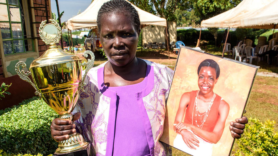 Agnes Tirop's mother, pictured here with her portrait and a trophy at her home in Kapnyemisa.