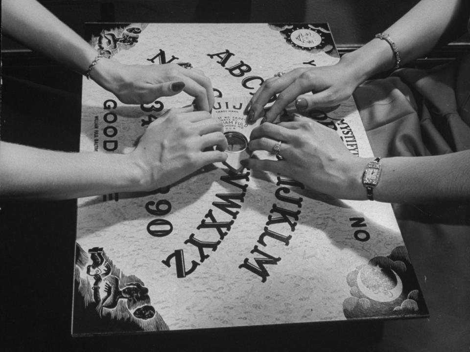 People playing with a Ouija Board.