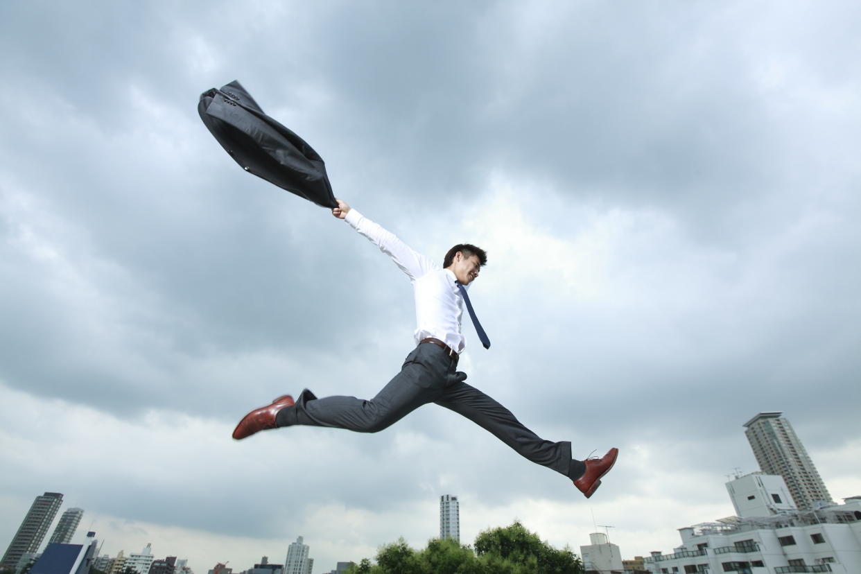 Asian man in suit jumping.