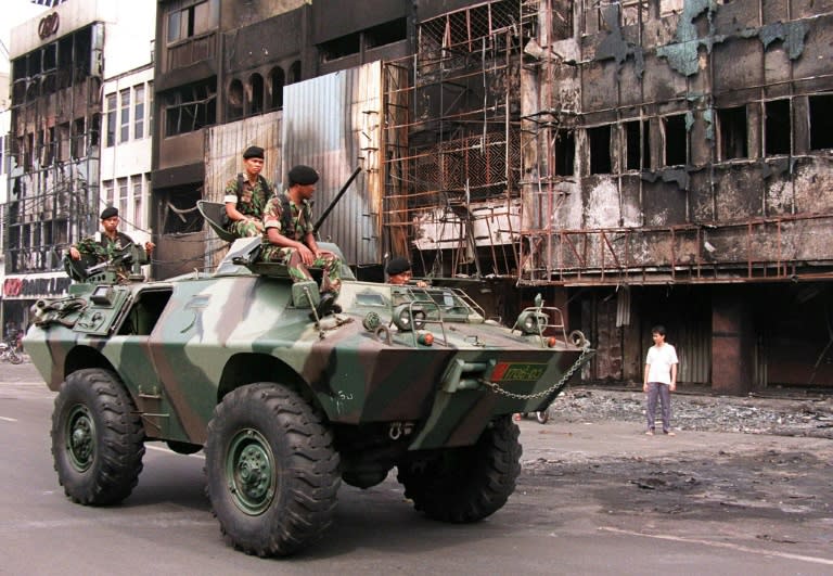 An armoured personnel carrier patrols a torched street in Jakarta's Chinatown after rioting in 1998