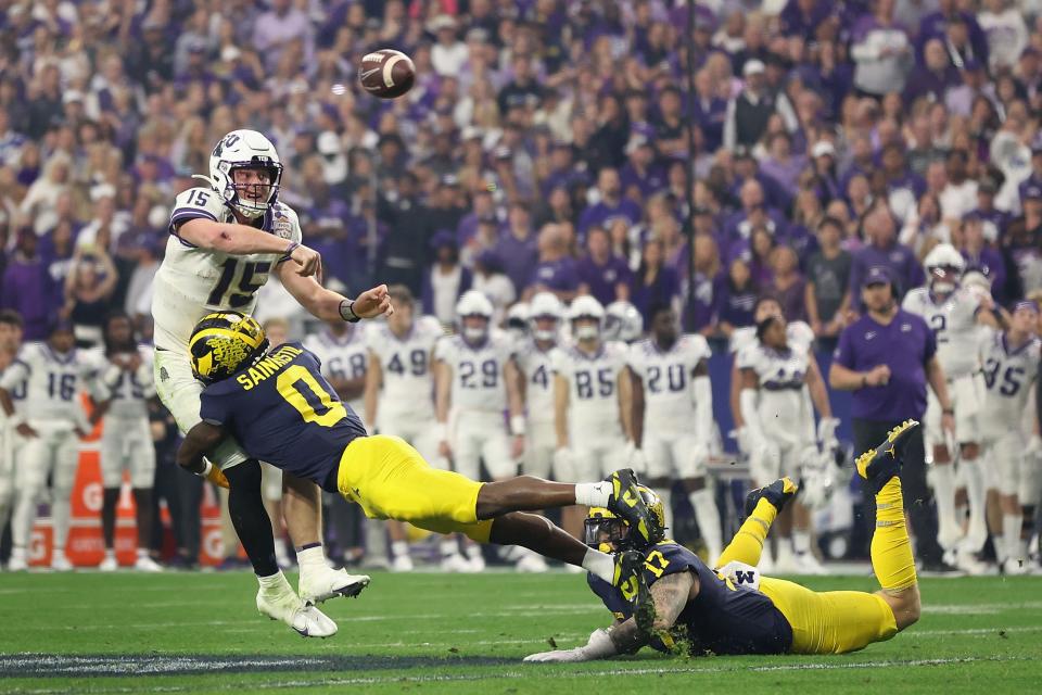 TCU quarterback Max Duggan (15) throws a pass under pressure from Michigan's Mike Sainristil (0) and Braiden McGregor (17) during the Horned Frogs' 51-45 win Saturday in the Fiesta Bowl in Glendale, Arizona.